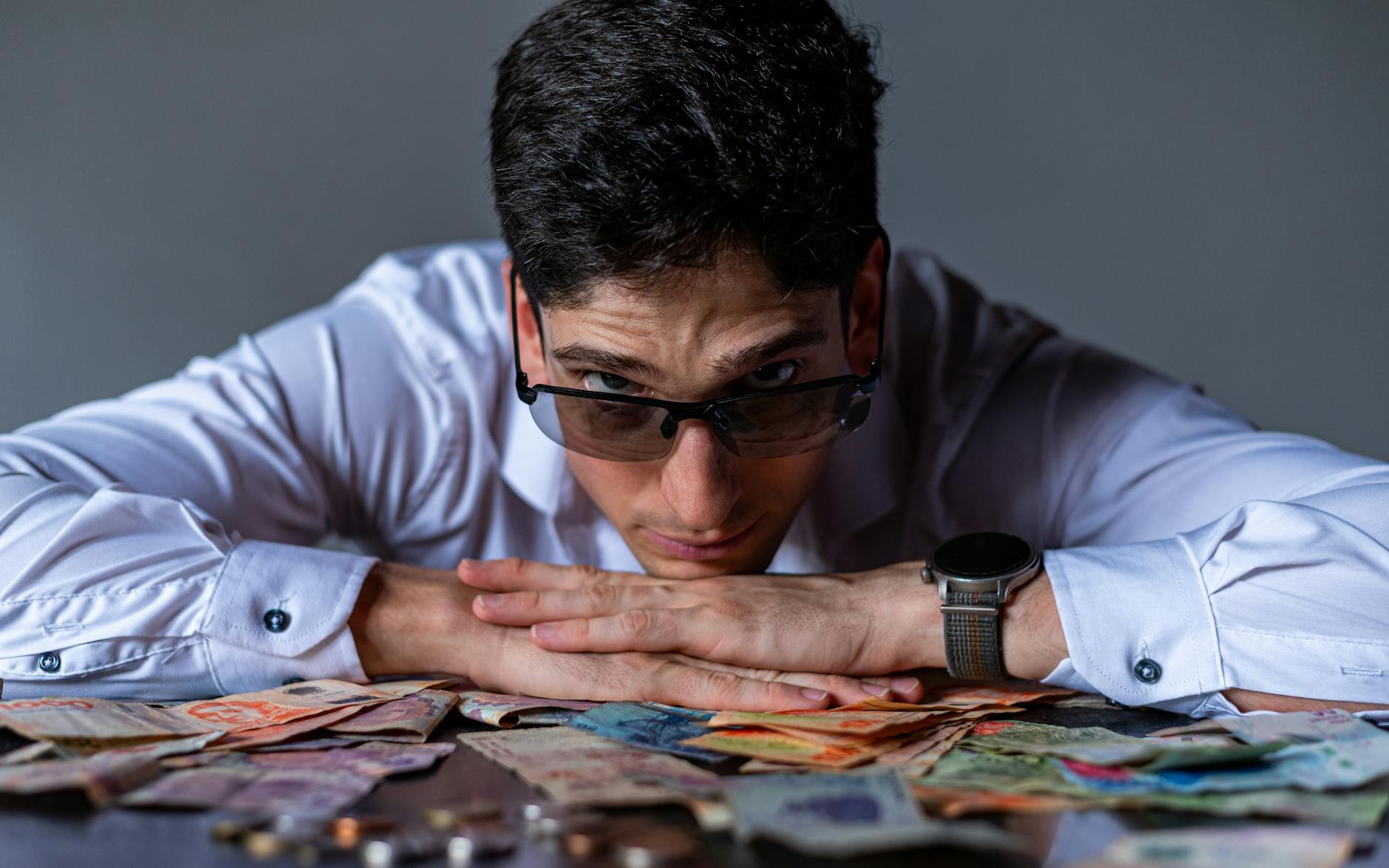 Zmęczony mężczyzna w okularach opiera głowę na stole z banknotami