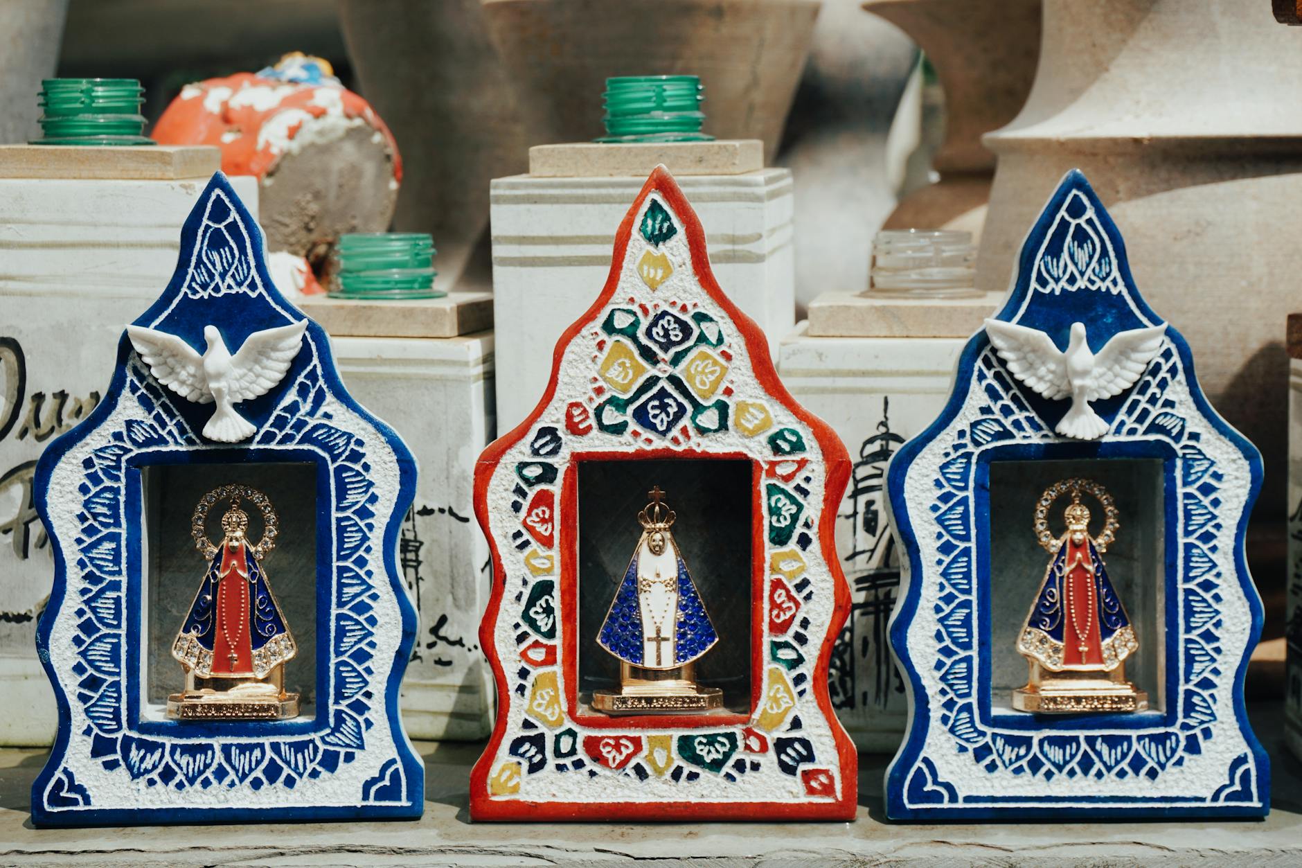 Figurki religijne z gołębiami w kolorowych, zdobionych ramkach