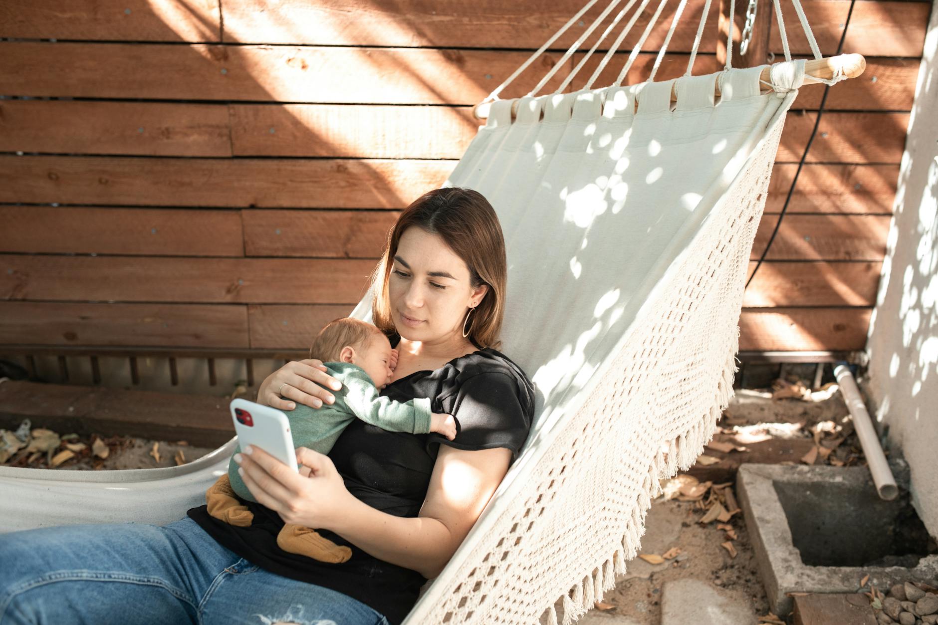 Mama buja się w hamaku z noworodkiem w ciche popołudnie na dworze
