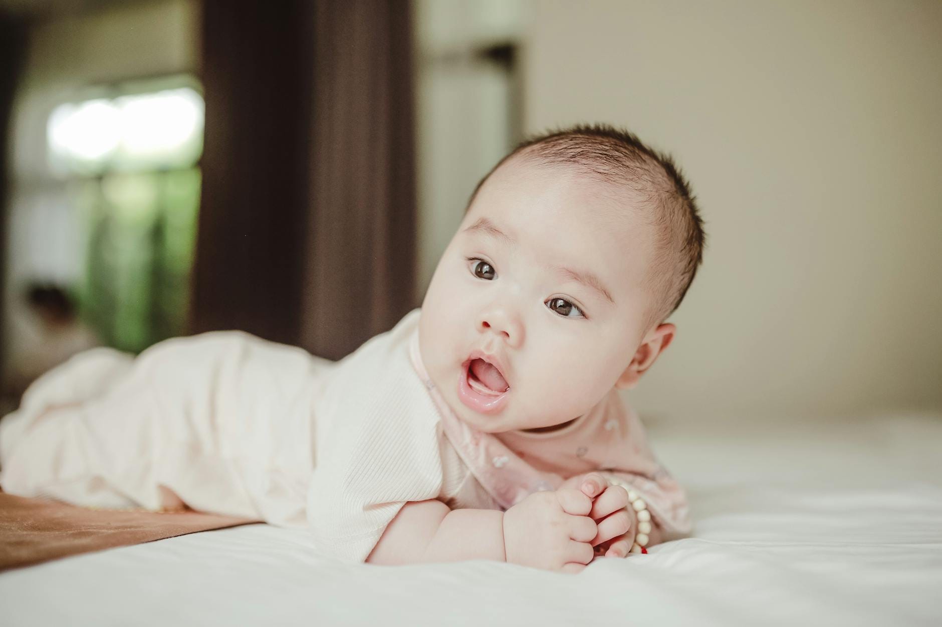 Niemowlę leży na łóżku i ciekawie rozgląda się wokół